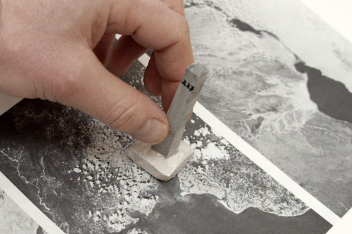 Nahaufnahme einer Hand, die eine Spielfigur in Turmform aus Beton in der Hand hält.